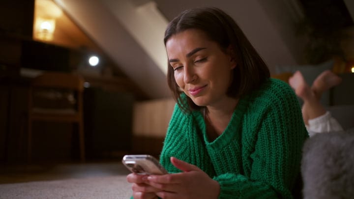 Woman Laughs While Texting in Cozy Home Setting