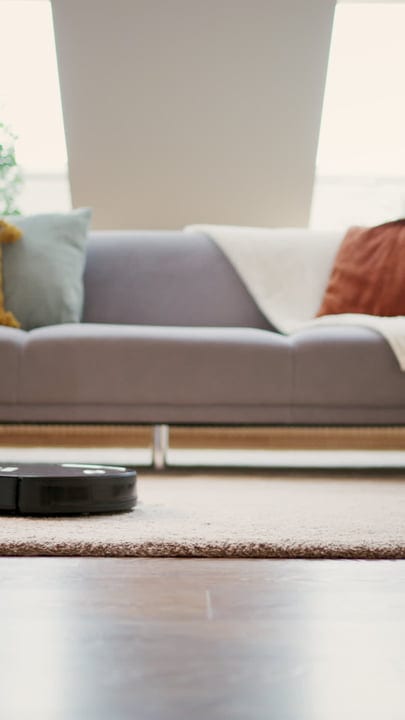 A Robot Vacuum Navigates a Cozy Living Room Scene