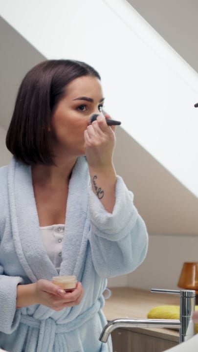 Morning Rituals: Woman Applies Makeup in Cozy Robe