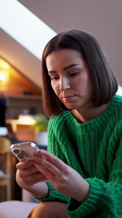 Focused Woman Engages with Her Smartphone in Cozy Attic