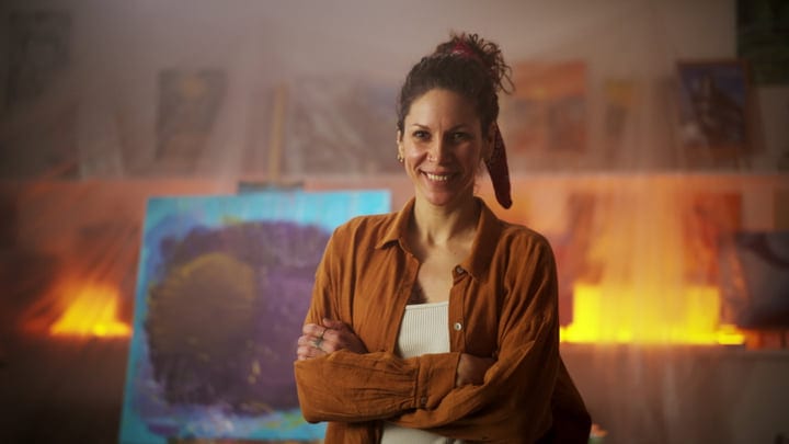 Artist Smiling Proudly Surrounded By Her Colorful Creations