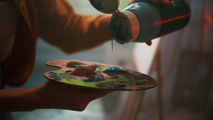 Artist Skillfully Blends Colors In A Sunlit Studio
