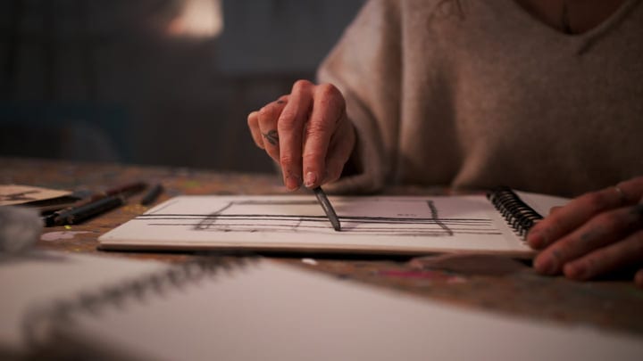 An Artist's Hand Sketching In The Warm Studio Light