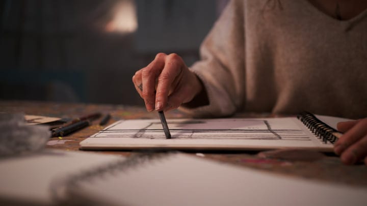Artist's Hand Sketching Lines In A Creative Studio