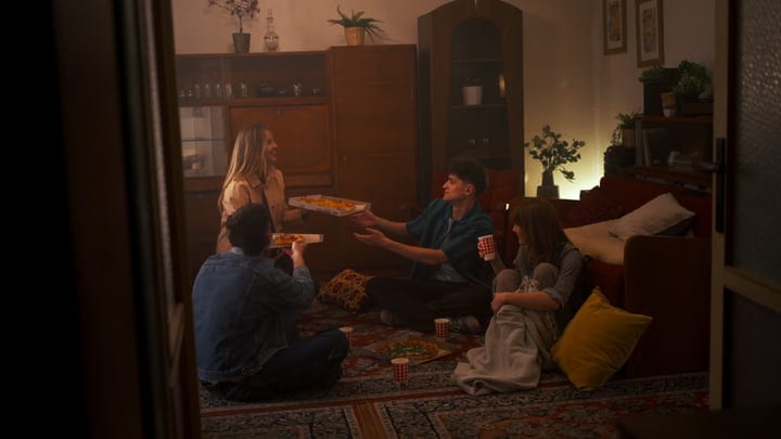 Friends Share Laughter And Pizza In A Warm Living Room