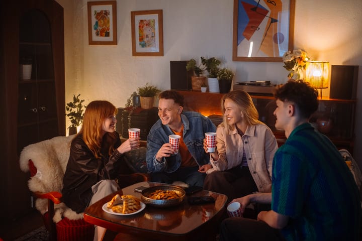Friends Share Laughter Over Warm Drinks Indoors
