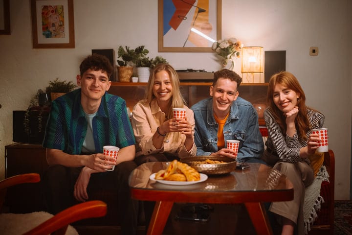 Warm Smiles Over Snacks In A Cozy Living Room