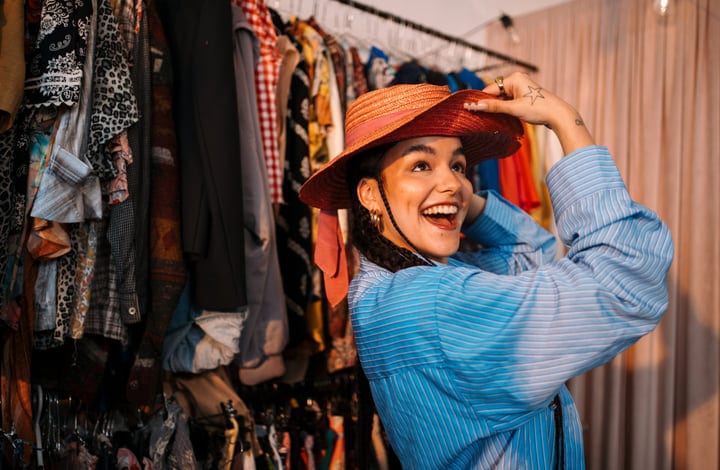 Joyful Woman Tries On Hat In Vibrant Boutique Setting