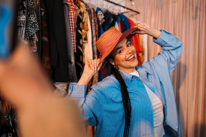 Joyful Shopper Tries On A Stylish Hat In Boutique