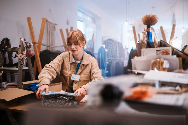 Young Woman Organizing Clothes In A Cozy Boutique