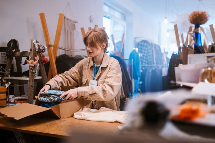 A Boutique Worker Carefully Wraps A Customer's Purchase
