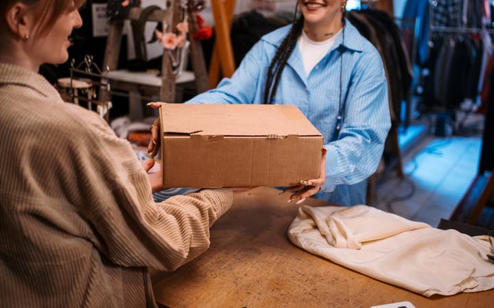 Joyful Exchange Of A Package In A Cozy Boutique
