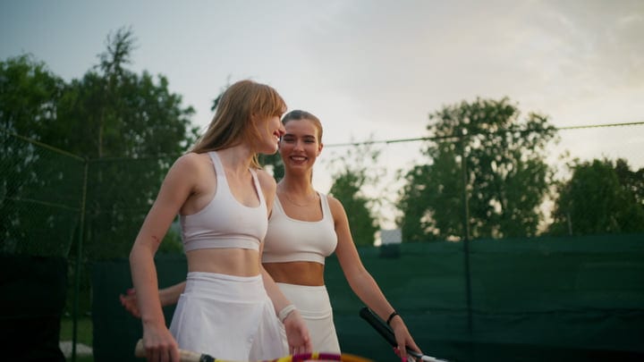 Friendly Women Tennis Players Chatting On Court With Rackets
