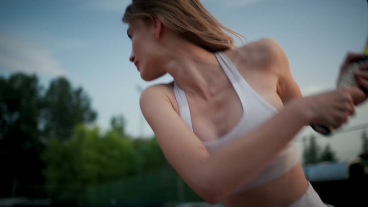 Woman In White Sports Top Serving Tennis Ball Outdoors