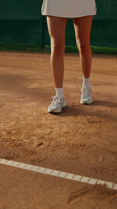 Female Tennis Player Standing on Red Clay Court Preparing to Serve