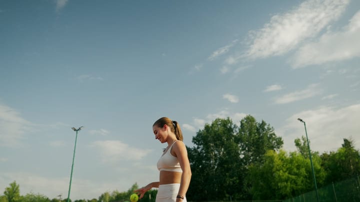 Young Woman Tennis Player Holding Ball Before Serve On Outdoor Clay Court