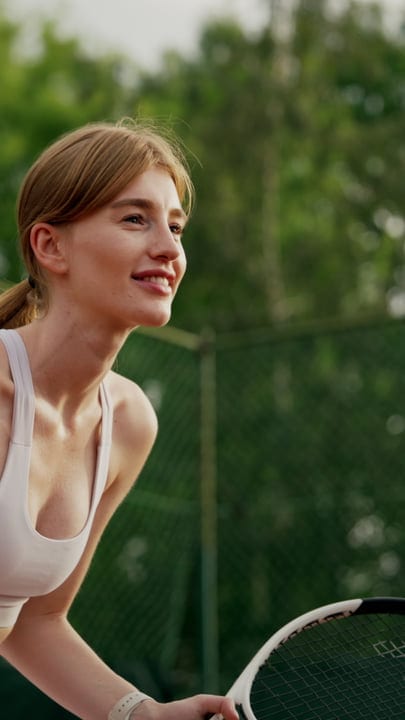 Active Young Woman Smiling With Tennis Racket On Green Outdoor Court