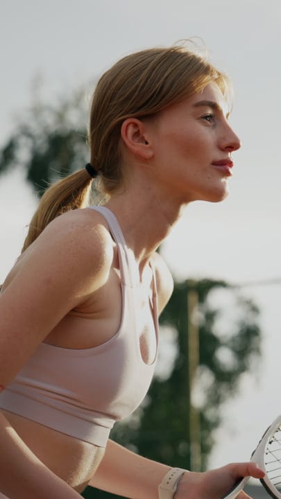 Determined Young Woman Poised To Serve A Tennis Ball Outdoors