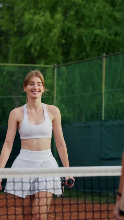 Smiling Woman In White Tennis Attire Stands On Outdoor Court