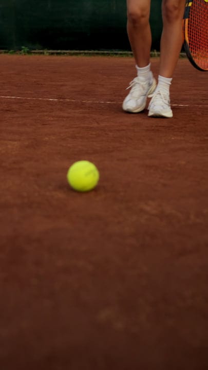 Close Up Of Tennis Player's Feet And Ball On Red Clay Court