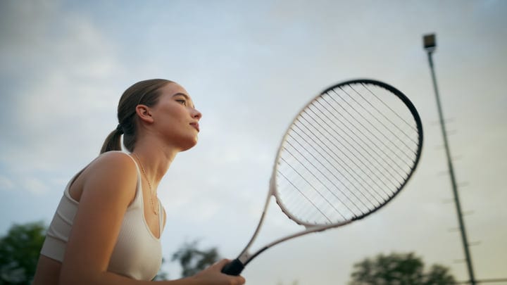 Dedicated Young Woman Prepares To Serve Tennis Ball On Outdoor Court