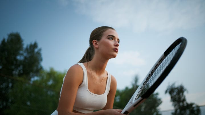 Female Tennis Player Concentrates On Ball During Game Outdoors