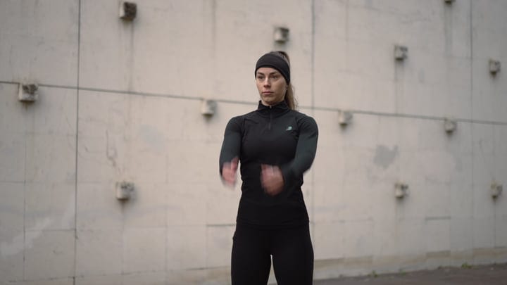 Active Woman Warming Up With Arm Swings Against A Concrete Urban Wall