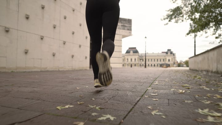 Runner's Legs On Autumn Path In Front Of European Building