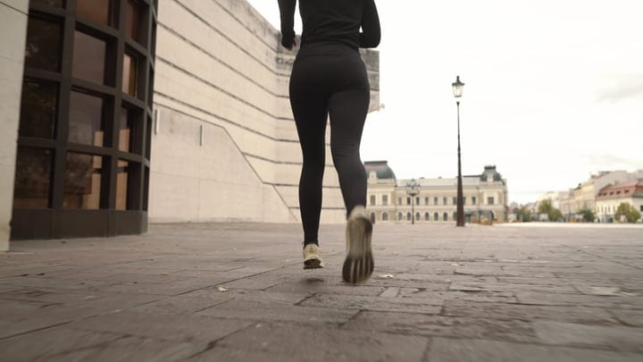 Woman Running In Black Activewear On European City Square