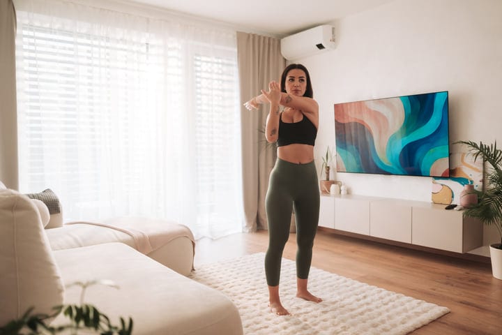 Young Woman Stretching Arm During Morning Exercise Routine At Home