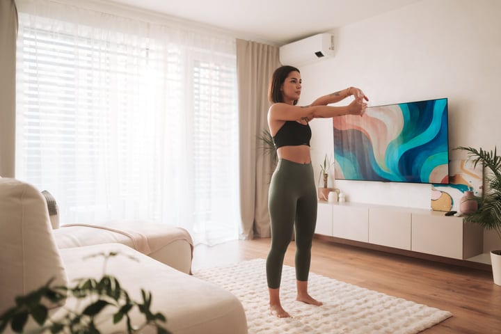 Woman Stretching Her Arms In Bright Apartment Living Room Interior