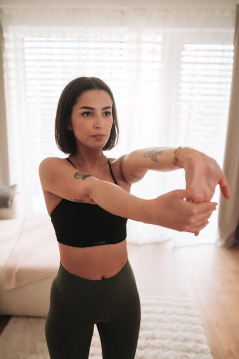 Woman Stretching Wrists While Warming Up For Exercise At Home
