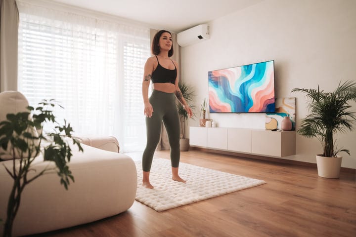 Young Woman Exercising In Her Bright Modern Living Room