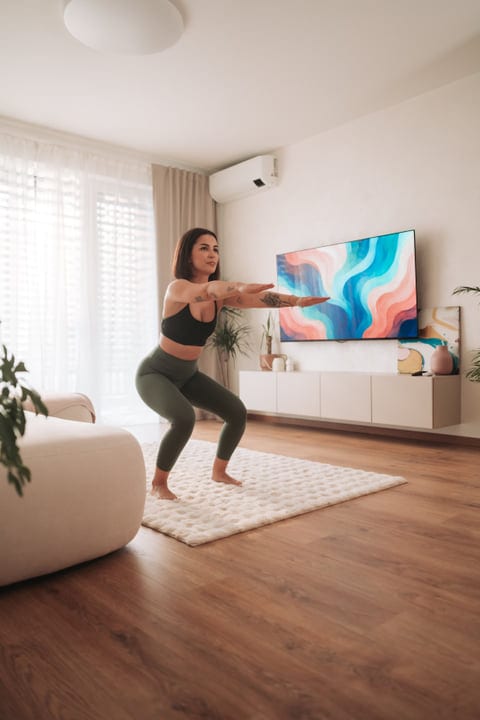Fit Woman Performing Squats In Her Contemporary Home Living Room