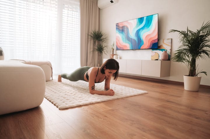 Young Woman Holds Plank Pose On Floor Mat In Bright Home Interior