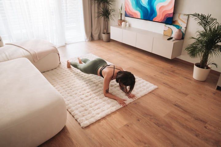 Young Woman Holds Plank Pose On Rug In Bright Living Room