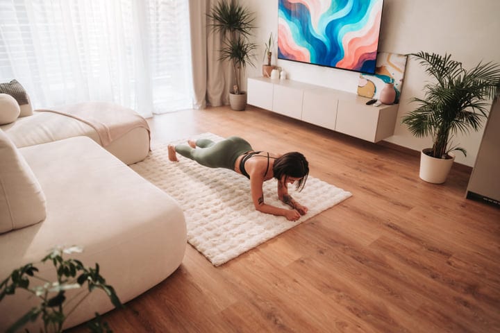 Young Woman Performing Core Plank Exercise On Rug In Her Bright Living Room