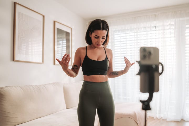 Woman Demonstrating Home Workout Routine For Online Audience In Bright Living Room