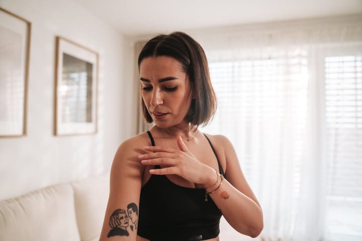 Woman Touching Her Arm After Workout In Bright Living Room
