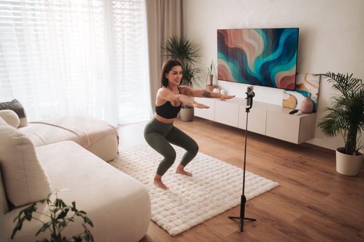 Young Woman Doing Squats For Home Workout In Modern Living Room