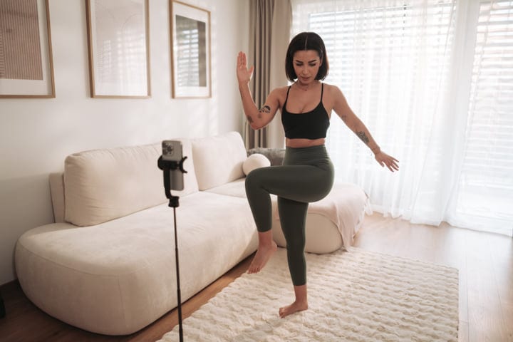 Woman Exercises At Home Guided By Phone In Bright Living Room