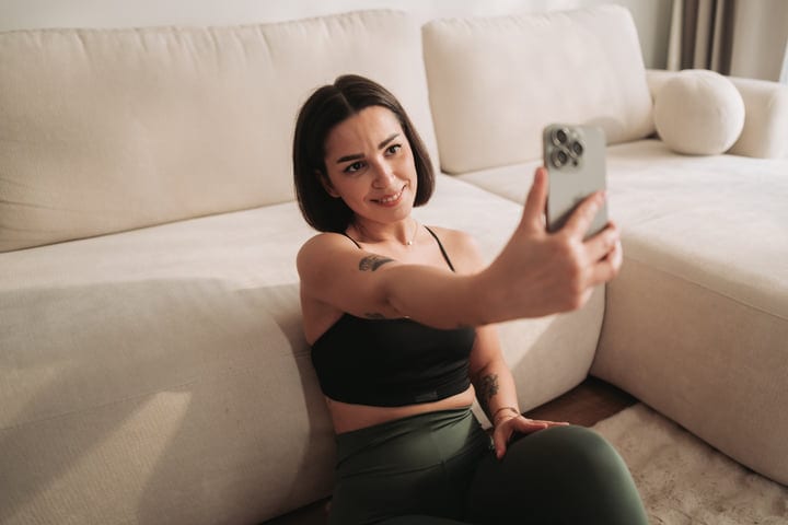 Smiling Woman In Sportswear Taking Selfie With Smartphone On Living Room Floor