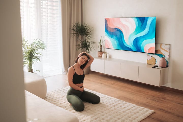 Young Woman Stretching Neck On Rug In Bright Modern Living Room
