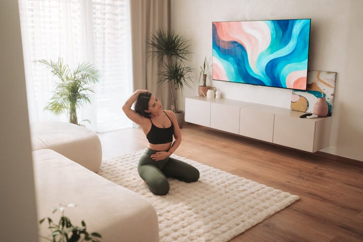 Young Woman Stretching Neck On Rug In Bright Modern Living Room