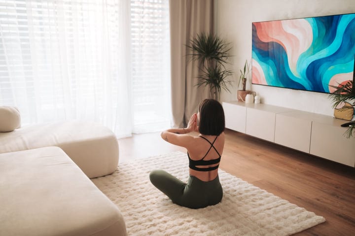 Woman Meditating On A Fluffy Rug In A Bright Modern Living Room