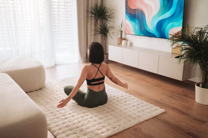 Young Woman Doing Morning Stretches On Rug In Sunny Apartment Interior