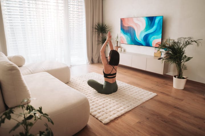 Woman Practicing Yoga In Her Bright Modern Living Room At Home