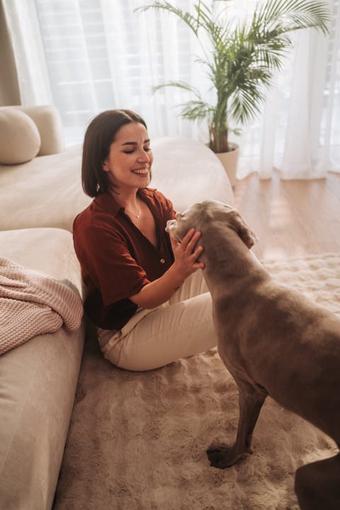 Woman Enjoying Morning Routine Petting Dog In Living Room