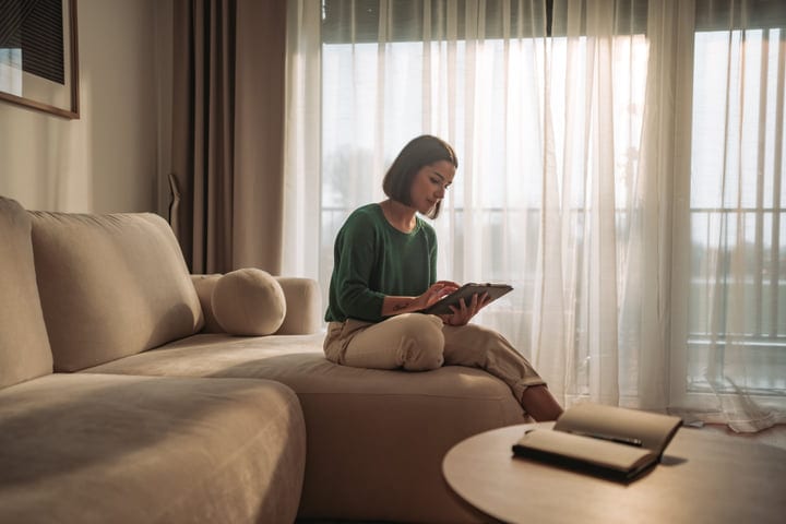 Young Woman Interacting With a Tablet on a Cozy Sofa in Her Home
