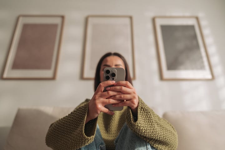 Woman Using Smartphone On Sofa In Cozy Living Room At Home